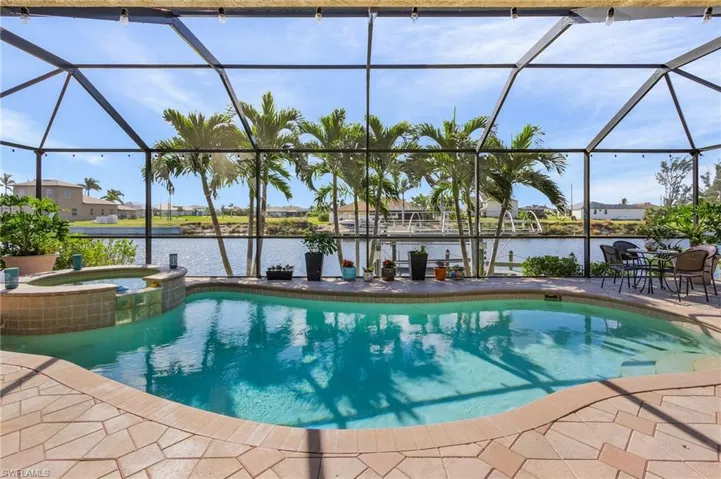View of swimming pool with an in ground hot tub, a patio, a water view, and glass enclosure