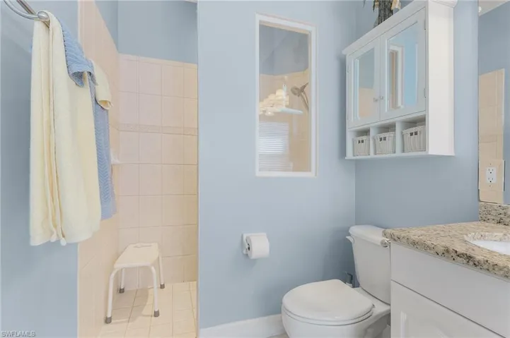 Bathroom with tile patterned floors, vanity, a tile shower, and toilet