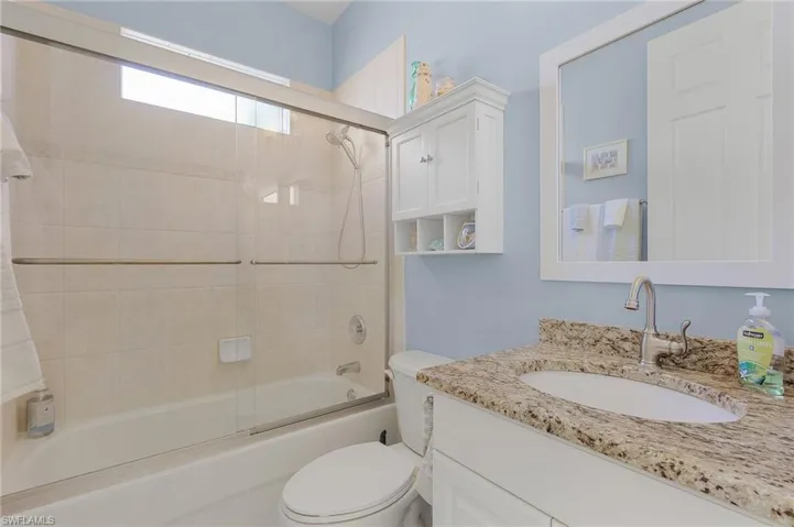 Full bathroom featuring vanity, bath / shower combo with glass door, and toilet
