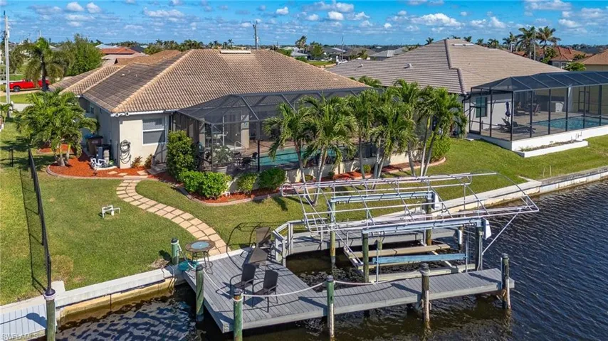 View of dock featuring a lawn, glass enclosure, a water view, and a swimming pool