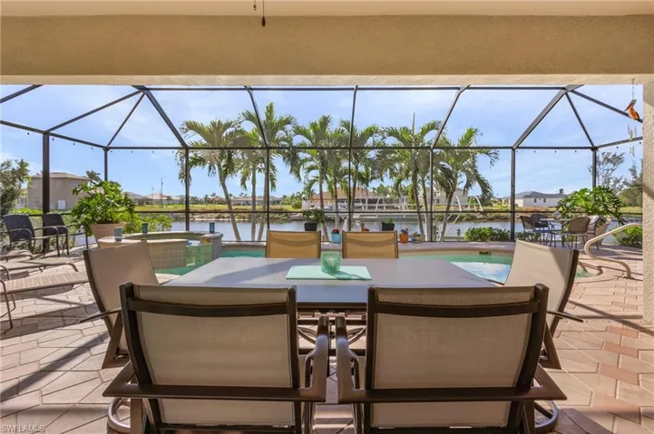 View of patio / terrace with glass enclosure, a swimming pool with hot tub, and a water view