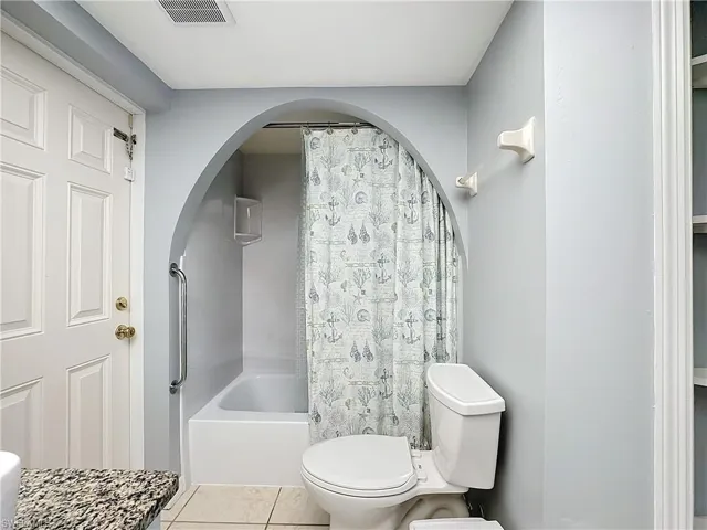 Bathroom with toilet, visible vents, tile patterned flooring, and shower / bath combo with shower curtain