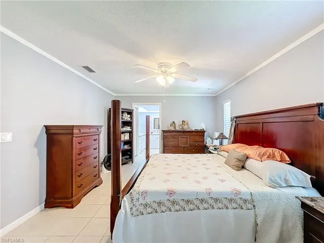 Bedroom with visible vents, crown molding, baseboards, ceiling fan, and light tile patterned floors