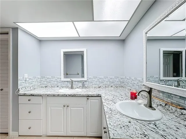 Bathroom with vanity, decorative backsplash, and a closet