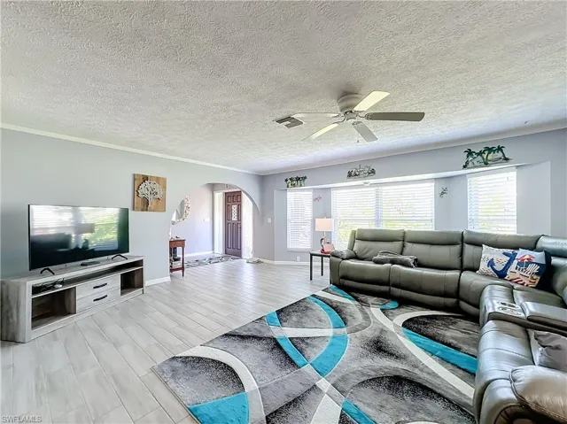 Living room with a healthy amount of sunlight, arched walkways, a ceiling fan, and visible vents
