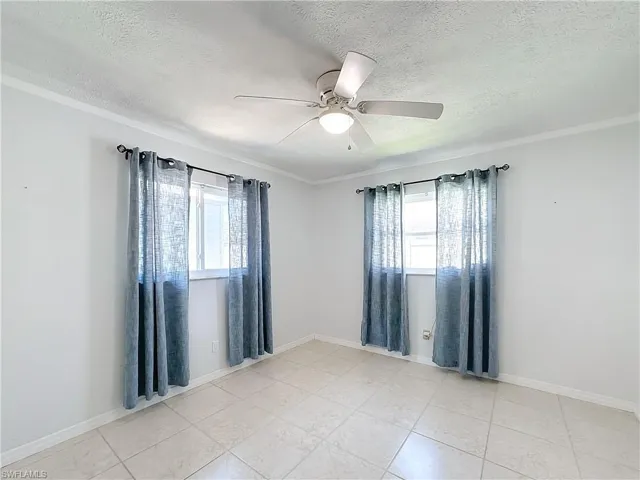 Unfurnished room with a healthy amount of sunlight, a ceiling fan, and a textured ceiling