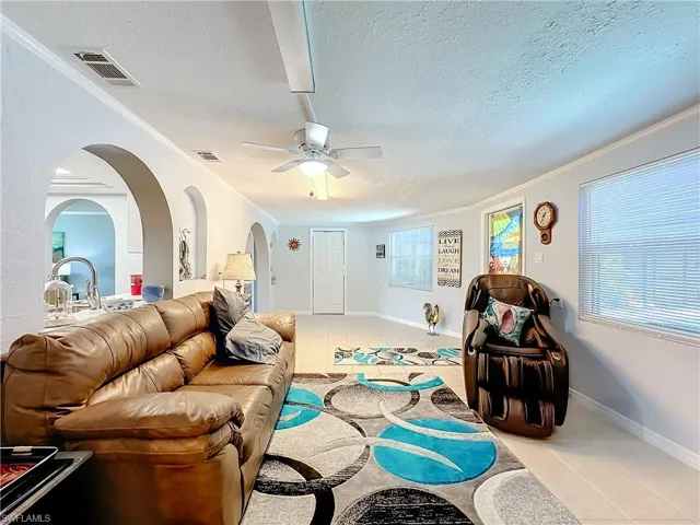 Living area featuring a textured ceiling, visible vents, and light tile patterned floors