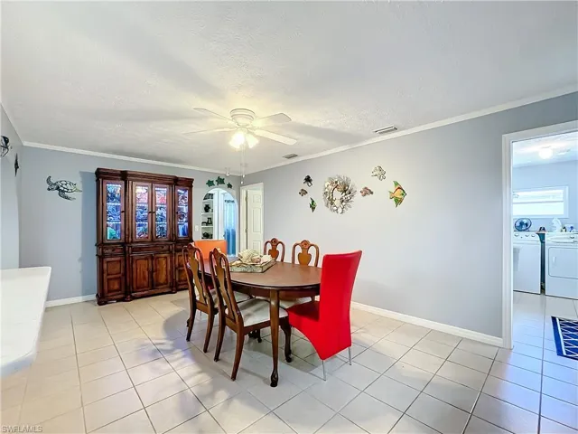 Dining space with separate washer and dryer, ceiling fan, light tile patterned flooring, and visible vents