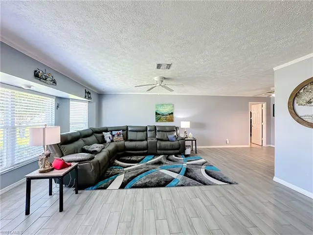 Living area featuring visible vents, a textured ceiling, ceiling fan, and wood finished floors