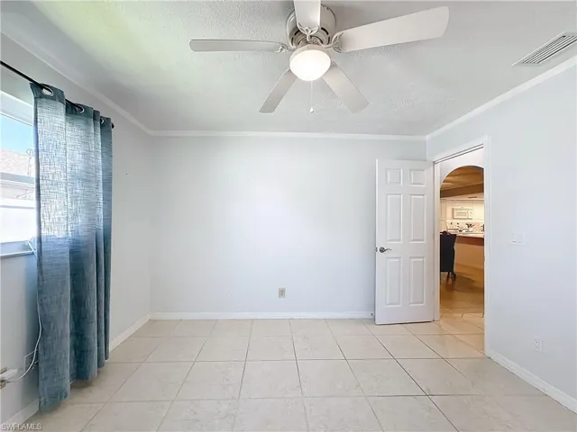 Spare room with arched walkways, a ceiling fan, visible vents, and a textured ceiling