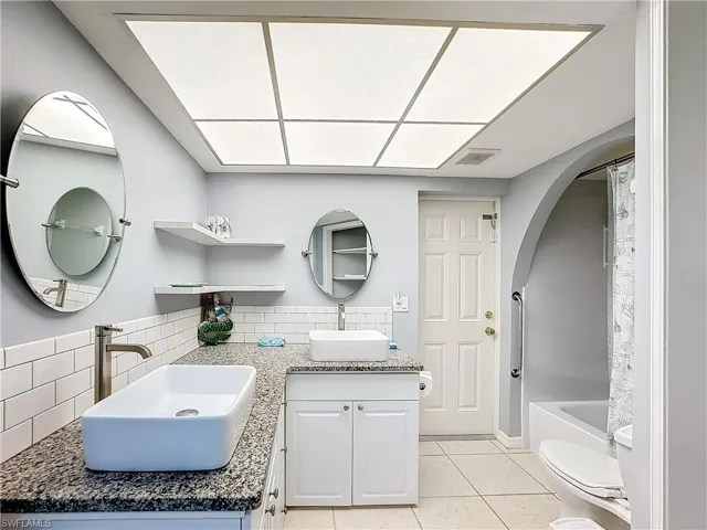 Bathroom with visible vents, vanity, toilet, tile patterned floors, and tasteful backsplash
