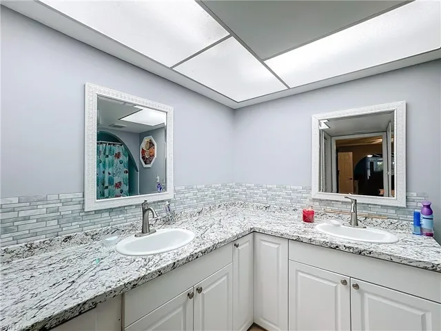 Bathroom with double vanity, a sink, and backsplash