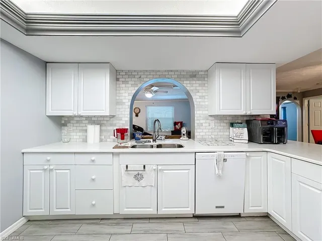 Kitchen with a sink, light countertops, decorative backsplash, and dishwasher