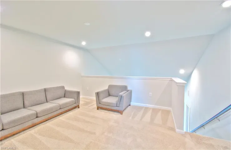 Living area with carpet, recessed lighting, vaulted ceiling, and an upstairs landing