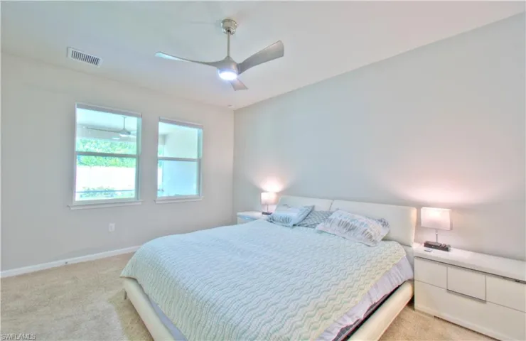 Bedroom with light colored carpet and a ceiling fan