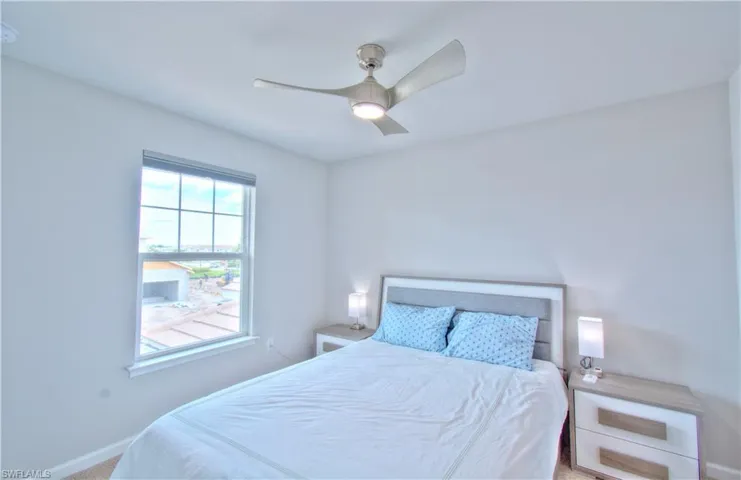 Carpeted bedroom with a ceiling fan and baseboards