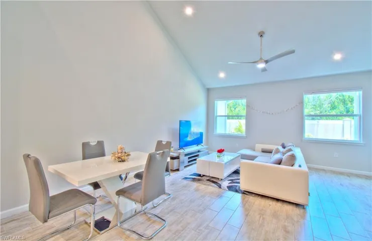 Living room with wood finish floors, ceiling fan, vaulted ceiling, and recessed lighting