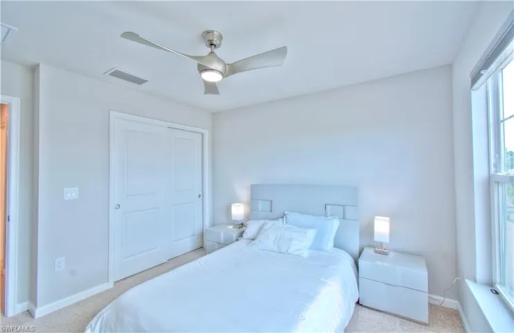 Bedroom with light colored carpet, a ceiling fan, and a closet