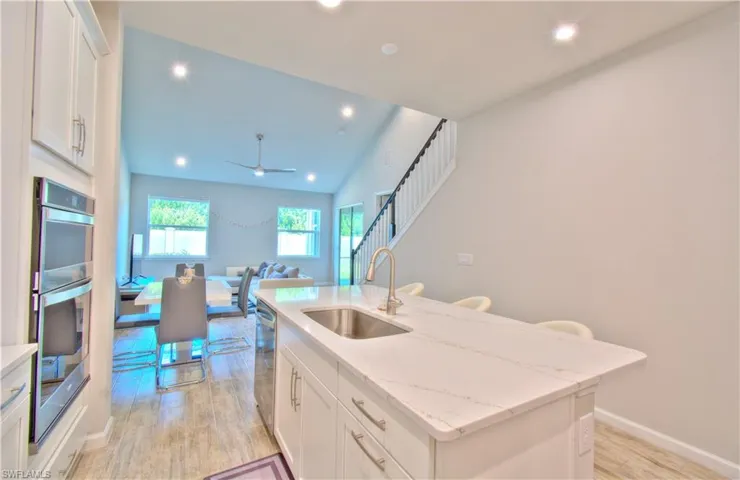 Kitchen with white cabinets, open floor plan, a center island with sink, light wood-style floors, and recessed lighting