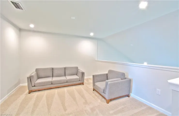 Living area with light carpet and recessed lighting