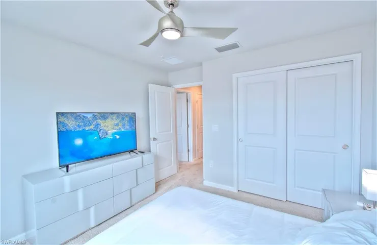 Bedroom featuring light colored carpet, a ceiling fan, and a closet