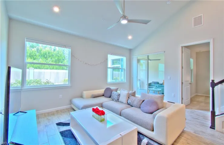 Living area with light wood-type flooring, ceiling fan, lofted ceiling, and recessed lighting