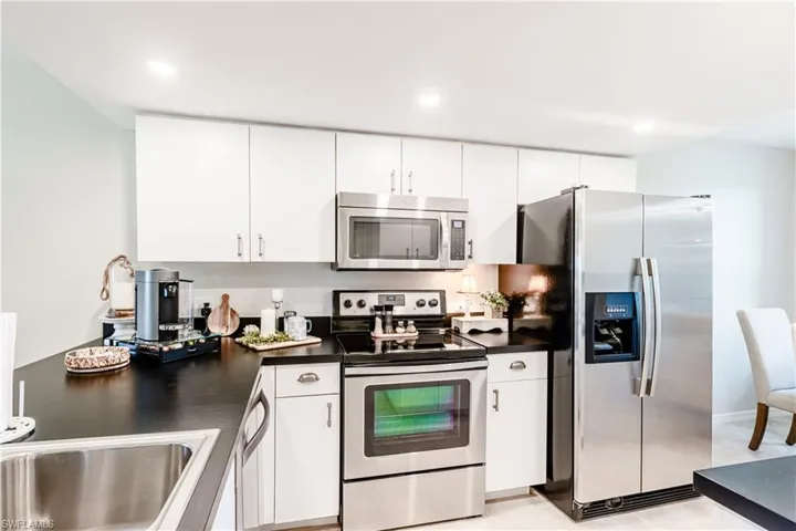 Kitchen featuring light tile patterned floors, white cabinetry, and stainless steel appliances
