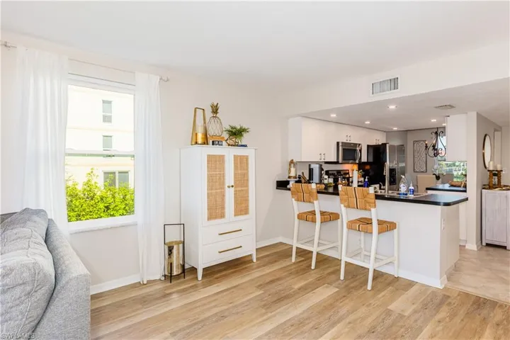 Kitchen featuring light wood-type flooring, kitchen peninsula, appliances with stainless steel finishes, a breakfast bar area, and white cabinets
