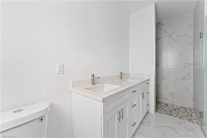 Bathroom with vanity, mirror doesn't show yet, toilet, and tiled shower
