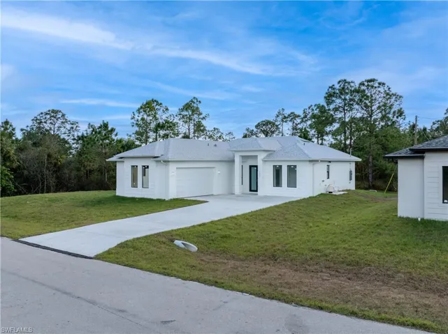 View of front of property with a garage and a front lawn