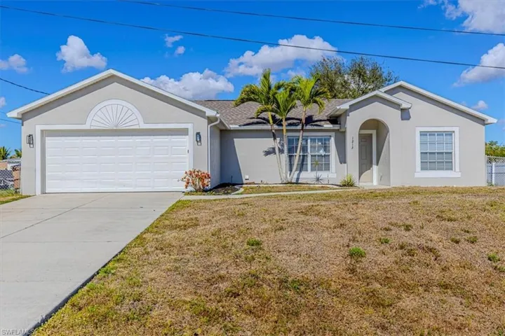 Ranch-style home with stucco siding, a front yard, an attached garage, and driveway
