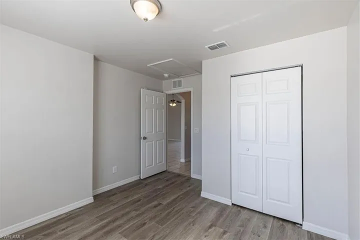 Unfurnished bedroom with attic access, light wood finished floors, and a closet