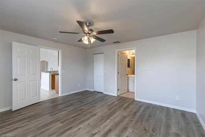 Unfurnished bedroom featuring light wood-type flooring, a ceiling fan, a closet, and ensuite bath