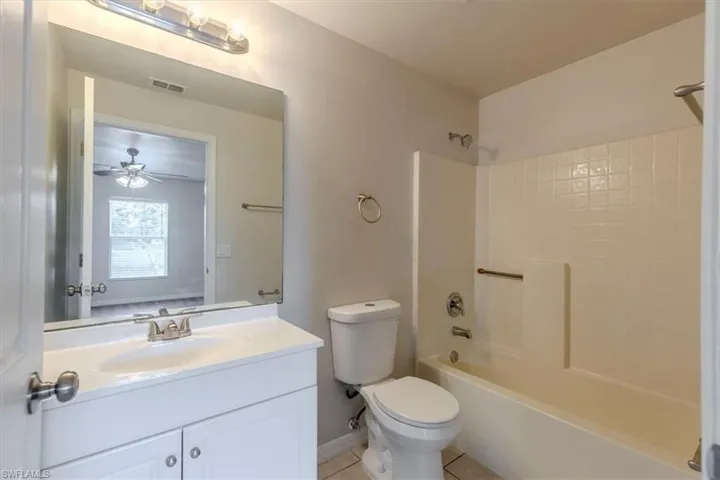 Full bath with vanity, shower / bath combination, light tile patterned floors, and a ceiling fan