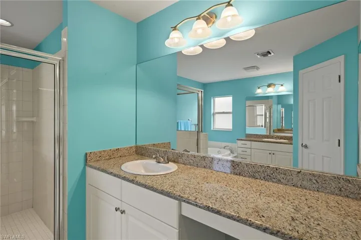 Bathroom featuring a stall shower, visible vents, vanity, and a bath