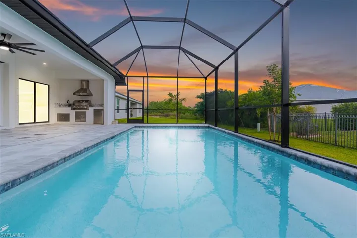 View of pool with glass enclosure, a sunroom, area for grilling, ceiling fan, and a patio area