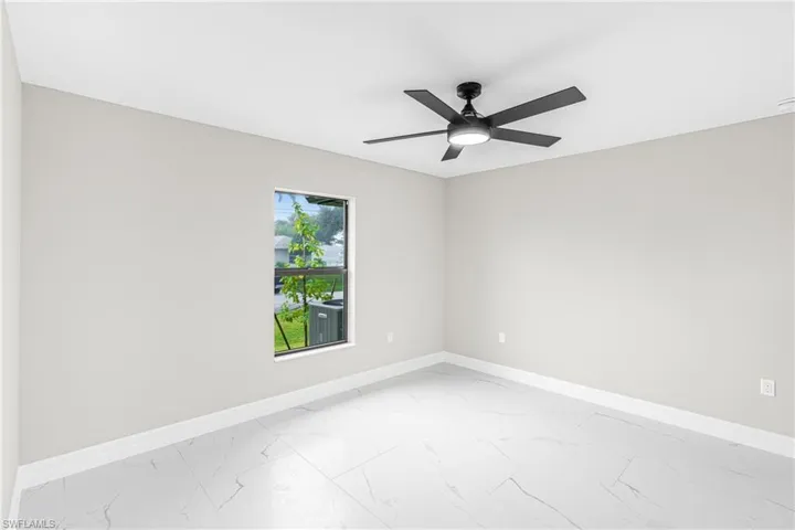 Empty room featuring light marble finish floors and ceiling fan