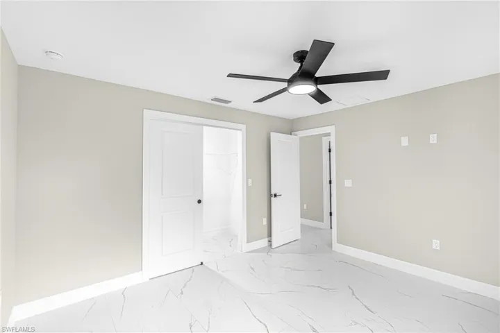 Unfurnished bedroom with light marble finish flooring, ceiling fan, and a closet