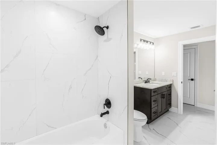 Full bathroom with vanity, light marble finish flooring, and shower / washtub combination