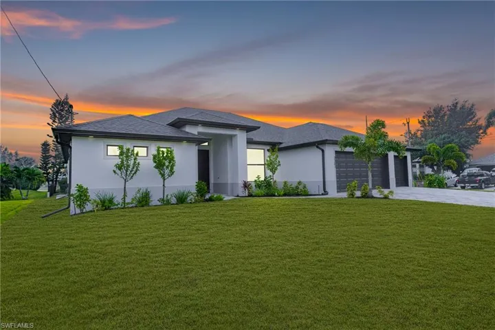 Prairie-style home featuring a yard, stucco siding, driveway, and a garage