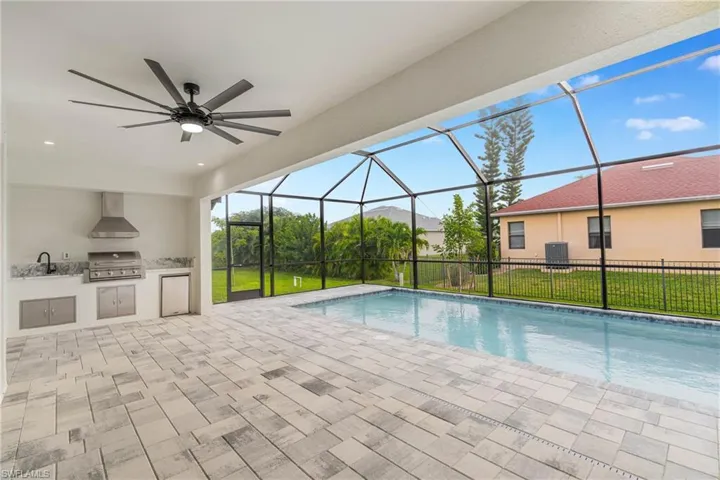 View of pool with area for grilling, a patio, a ceiling fan, a sunroom, and a lawn