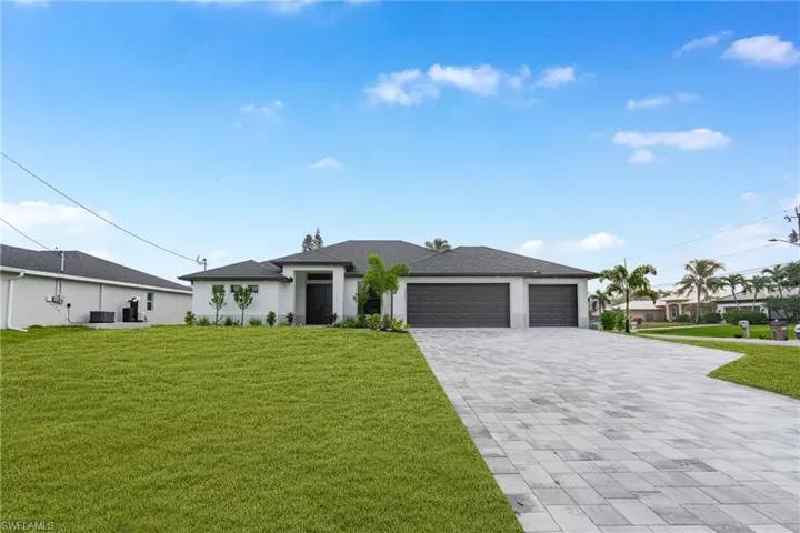 Prairie-style house with a front yard, a garage, decorative driveway, and stucco siding