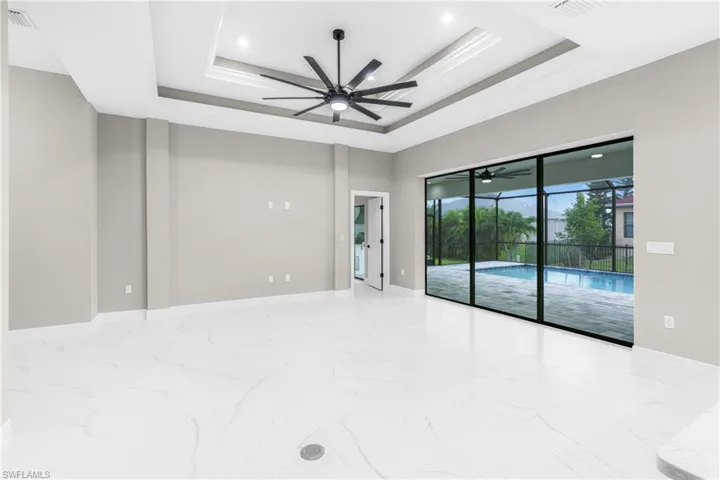 Unfurnished room featuring a raised ceiling, a ceiling fan, light marble finish floors, recessed lighting, and a sunroom