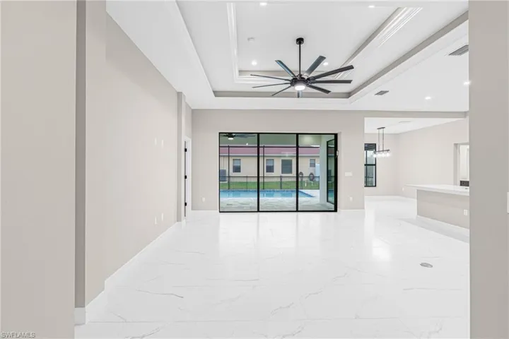 Spare room featuring light marble finish flooring, a tray ceiling, ceiling fan, and recessed lighting