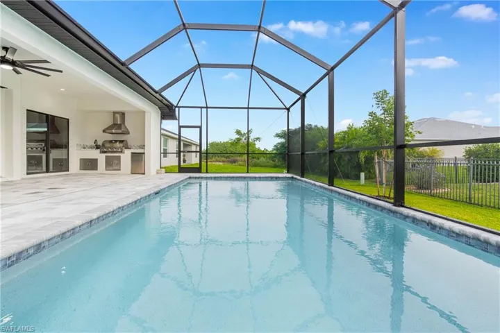 Outdoor pool with a lanai, exterior kitchen, a ceiling fan, a sunroom, and a patio