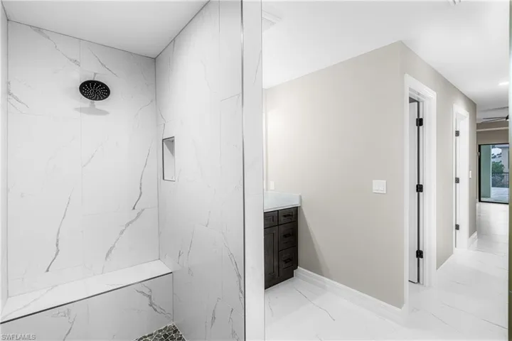 Bathroom with a marble finish shower, marble finish floors, vanity, and recessed lighting