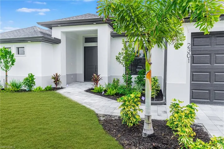 Doorway to property featuring stucco siding, a yard, and a garage