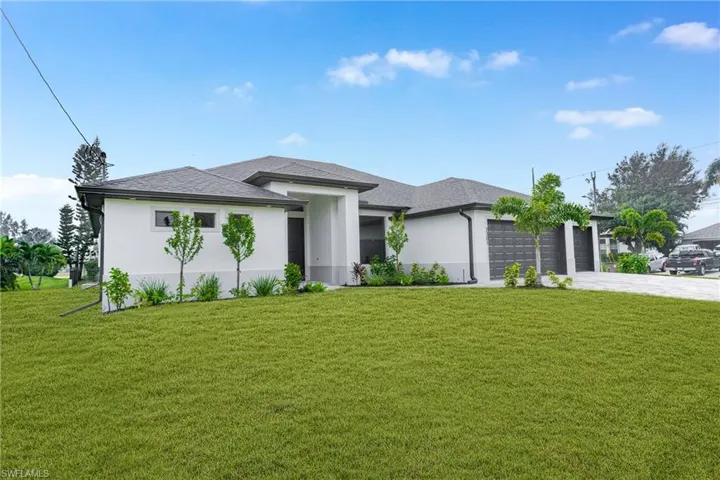 Prairie-style home featuring a front yard, driveway, stucco siding, and an attached garage