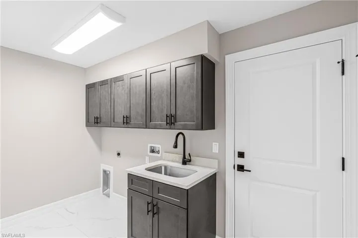 Laundry area featuring cabinet space, light marble finish floors, electric dryer hookup, and washer hookup