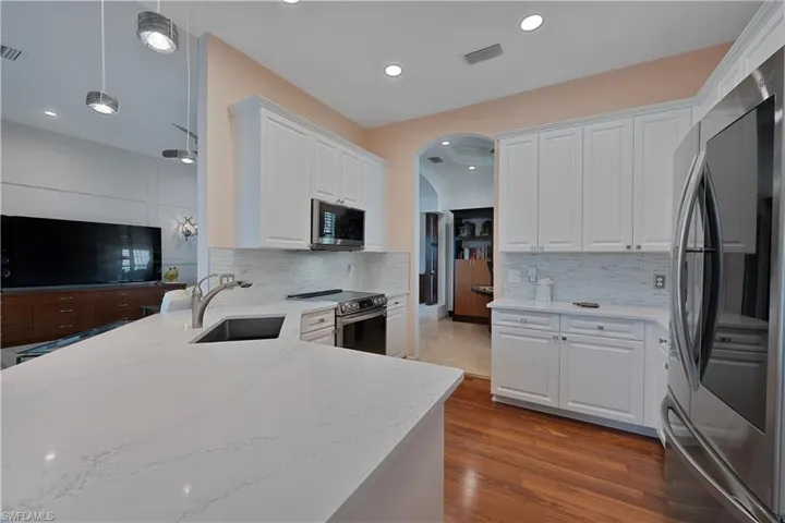 Kitchen featuring stainless steel appliances, a sink, white cabinets, light stone countertops, and recessed lighting